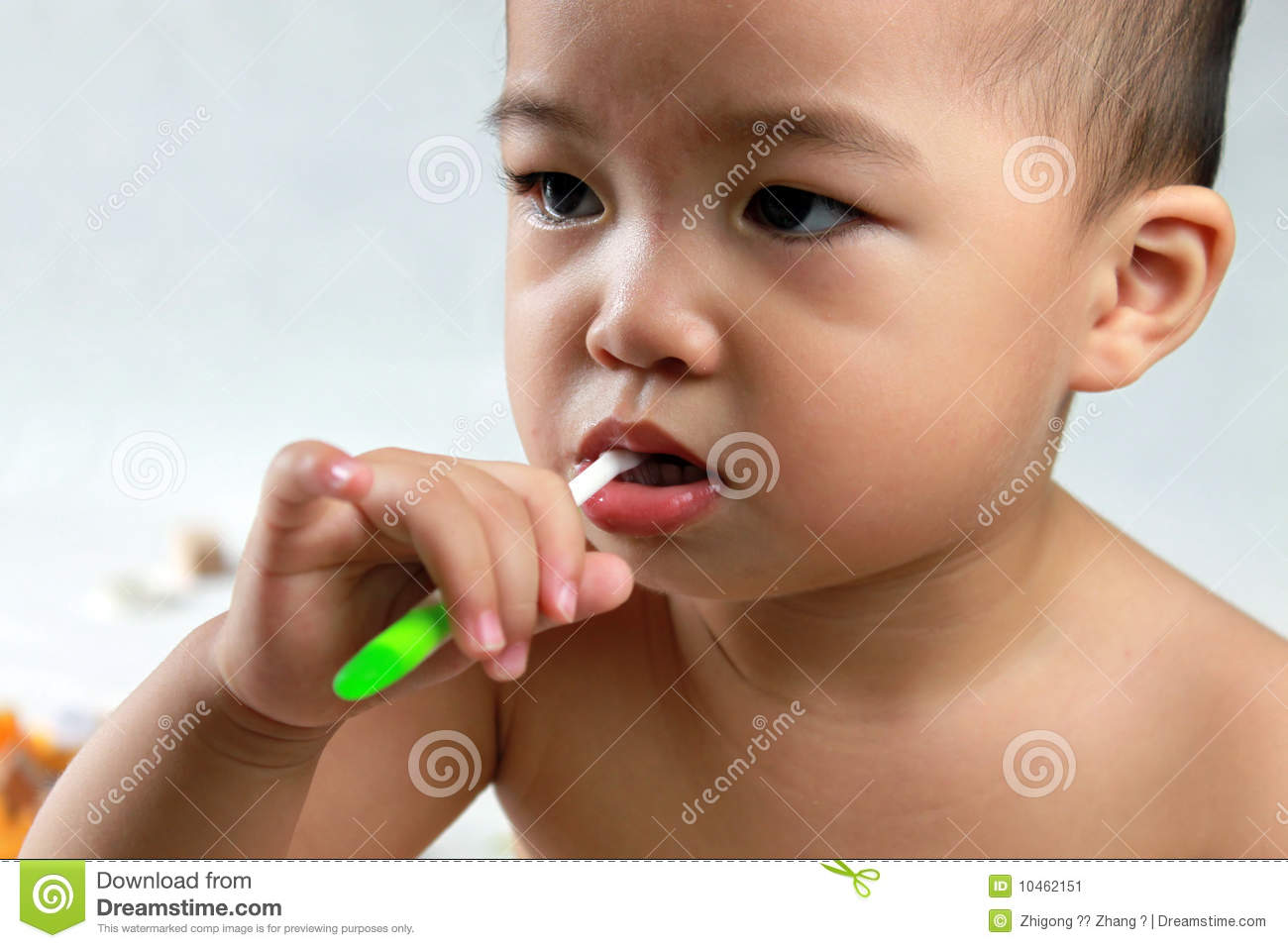 Year Old Asian Baby Brushing Teeth With A Green Toothbrushstaring