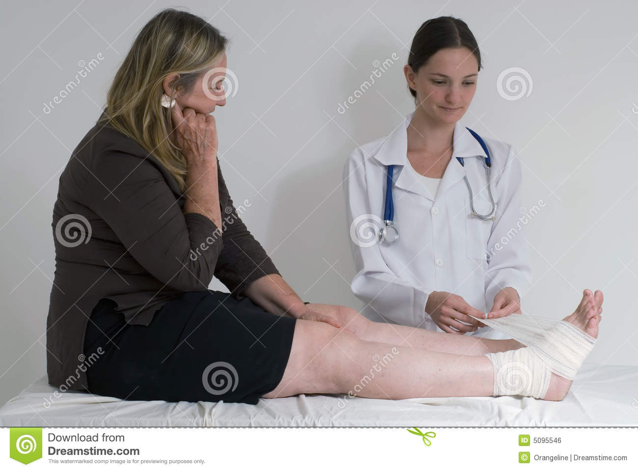 Shot Of A Doctor Nurse Wrapping Up A Female Patient S Sprained Ankle