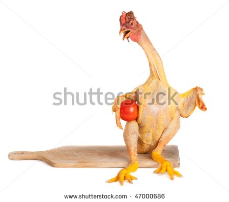 Raw Full Length Chicken Standing On Cutting Board And Holding Tomato