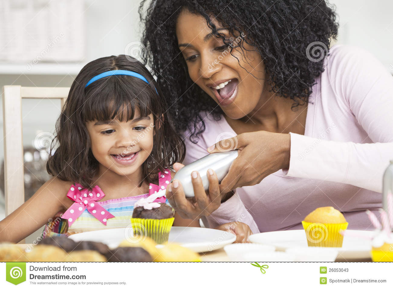 African American Mother And Mixed Race Daughter Having Fun Frosting