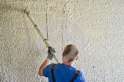 Worker Using A Sprayer Tool To Apply Concrete Stucco To A Large Wall