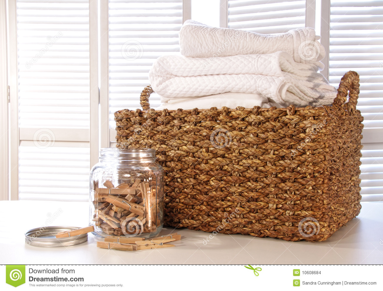 Laundry Basket With Linens On Table With Clothespins In Jar
