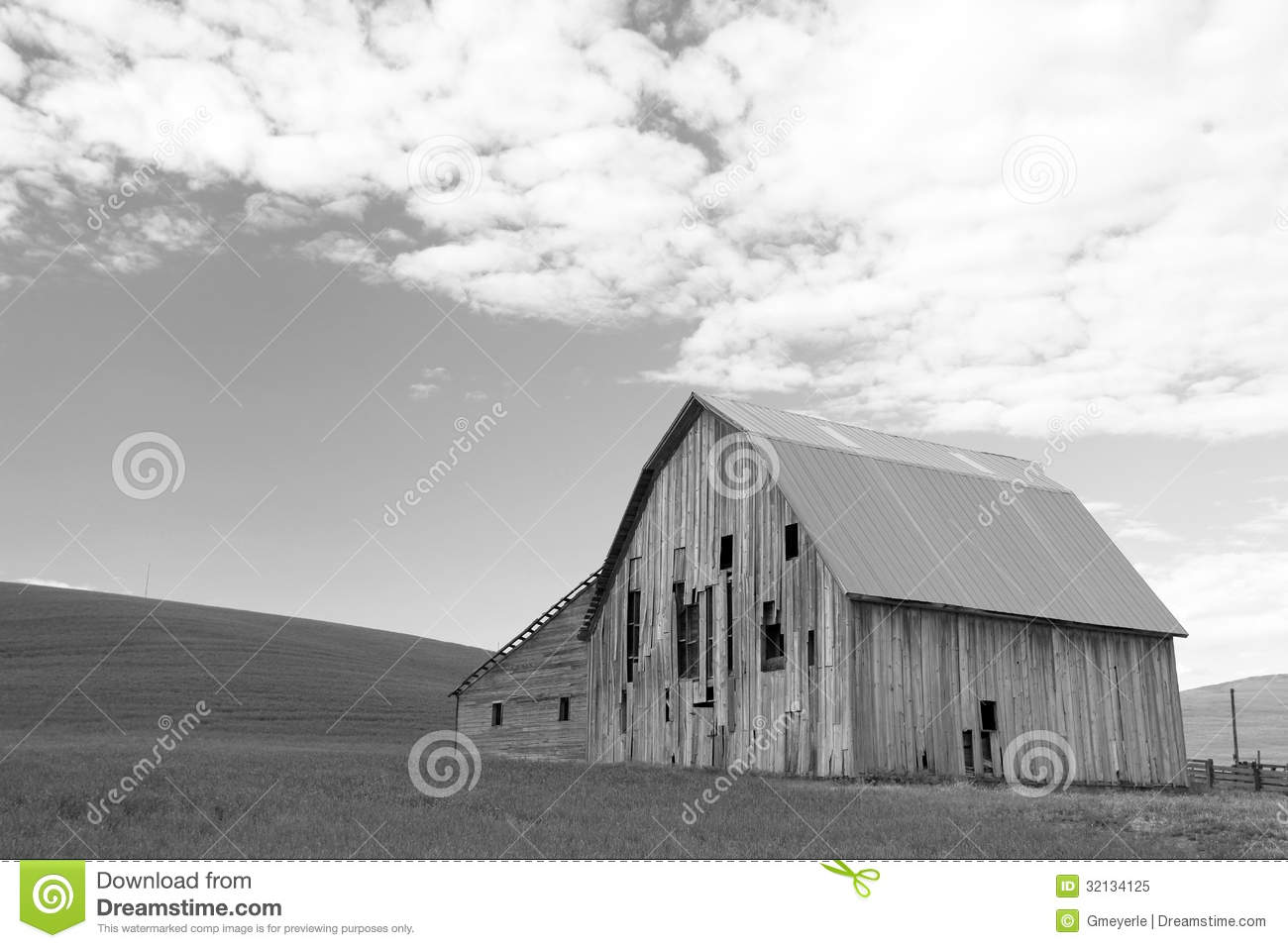Barn In Hilly Field With Sky Filled With Puffy Clouds In Background