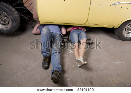 Man And Woman Working Under A Car Together With Their Legs Sticking