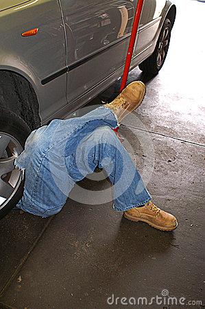 Man With His Legs Crossed As He Works Under A Car