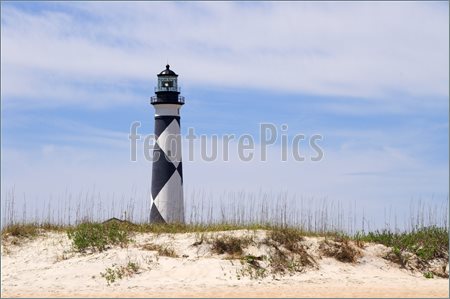 Picture Of A Historic Lighthouse Guiding Ships Away From Rocky Shoals