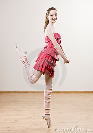 Ballerina In Frilly Dress And Leg Warmers Balancing On Toe In Dance
