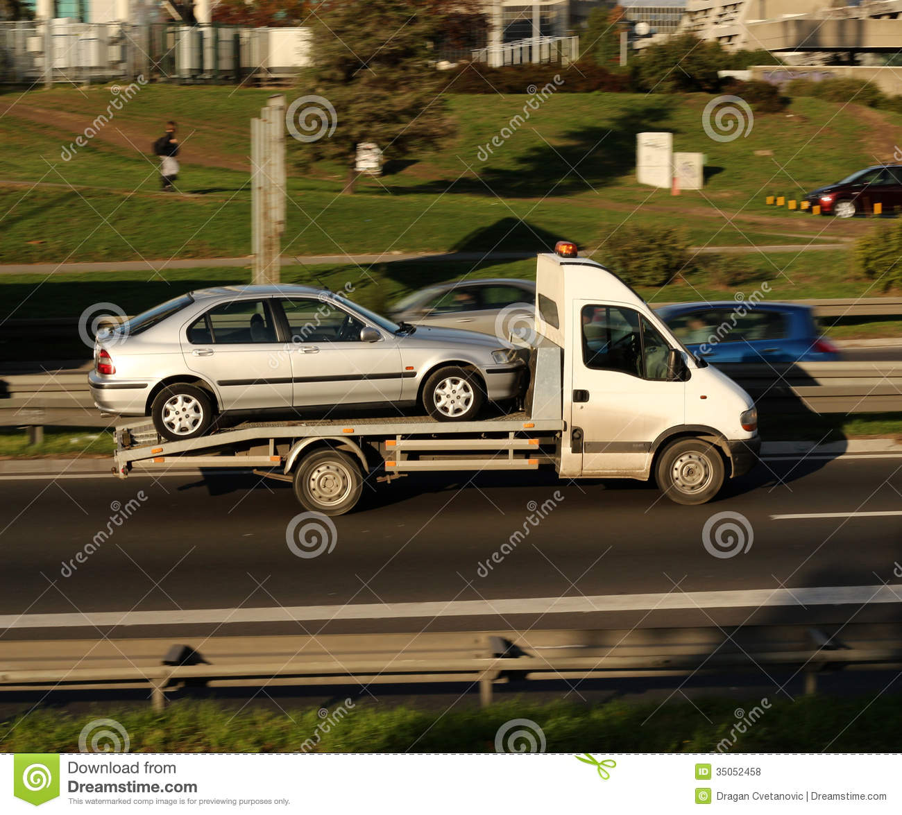 Silver Car Being Towed On A Towing Truck Speeding On A Highway