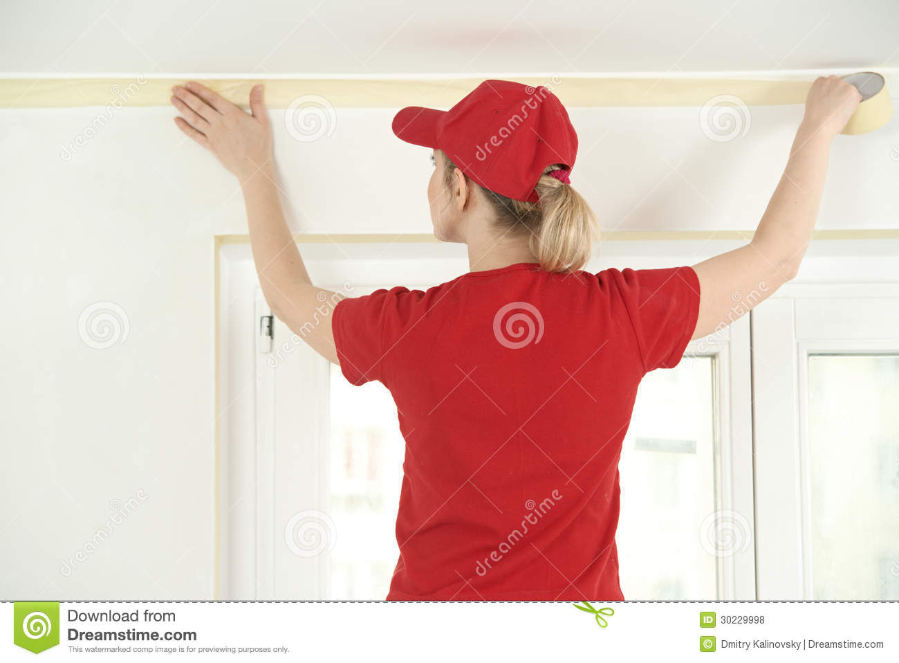 Woman Painter Worker Protecting Ceiling Moulding With Masking Tape