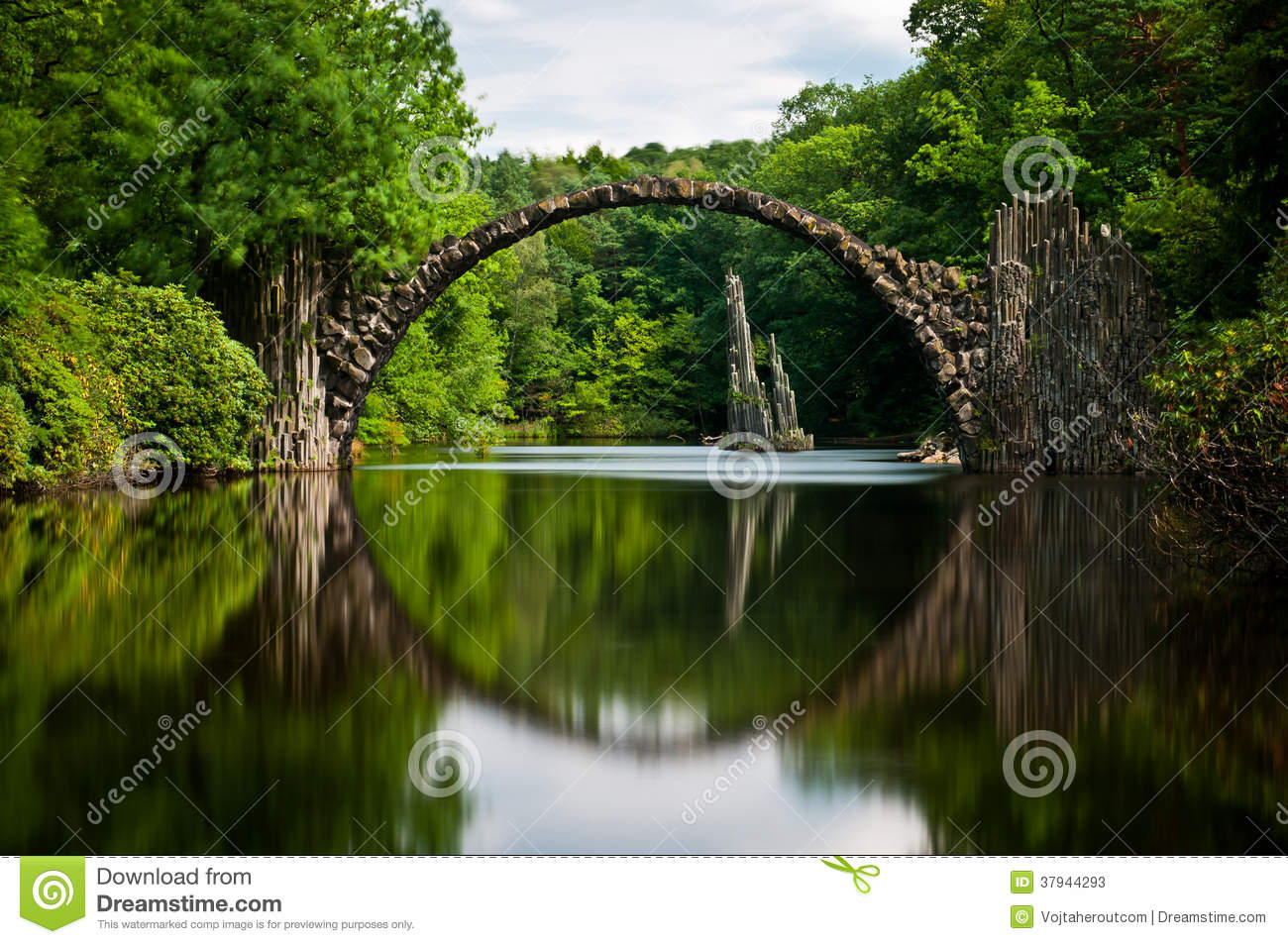 Old Stone Bridge Over The Quiet Lake With Its Reflection In The Water