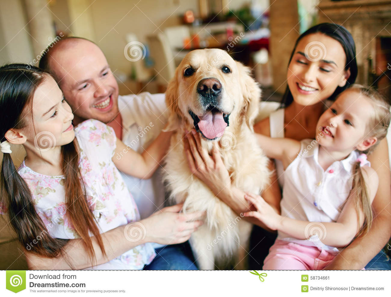 Young Friendly Family Of Four Cuddling Their Pet